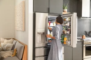 Photo of woman in kitchen reaching into refrigerator