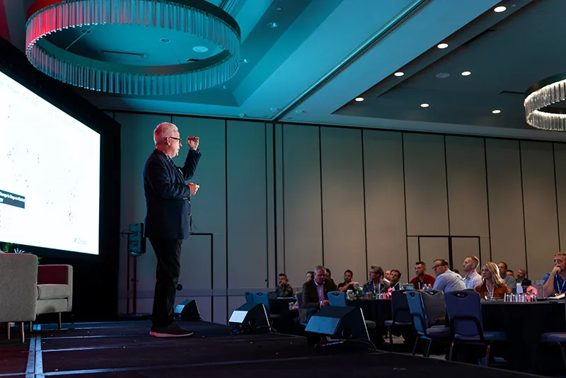 Man standing on staging speaking to audience