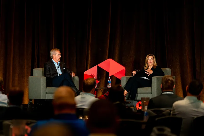 Man and woman on stage sitting in chairs and speaking to audience