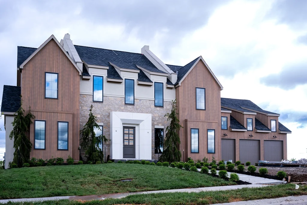 Newly built custom home with stone and wood siding, black-framed windows and a three-car garage.